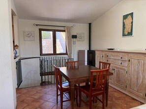 Ein Essbereich mit Holztisch und -stühlen, eine Küche mit Küchenschrank und ein Fenster mit Vorhängen.