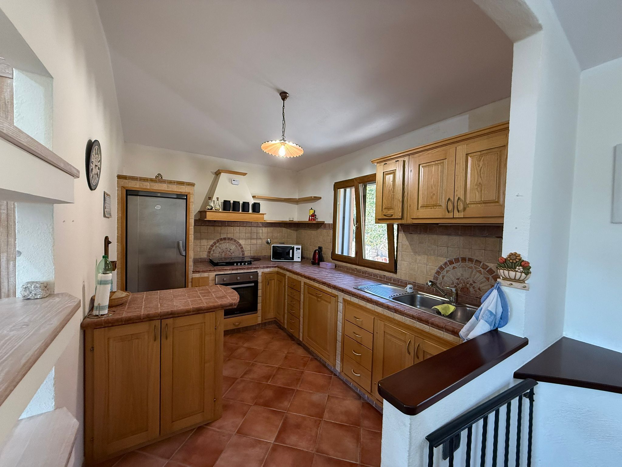 Una cucina con mobili in legno, un frigorifero in acciaio inossidabile, un forno a microonde e un fornello.