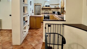 A spacious kitchen with a central island, wooden cabinets, and a tiled floor. - Villa Olbia surrounded by greenery.Perfect mix of peace and the sea Sardegna (Osseddu)
