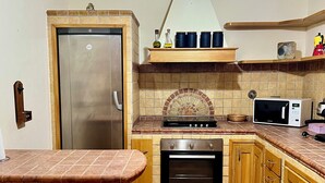 A kitchen with a stainless steel refrigerator, a stove, an oven, and a microwave. There is a wooden cabinet and a countertop. - Villa Olbia surrounded by greenery.Perfect mix of peace and the sea Sardegna (Osseddu)
