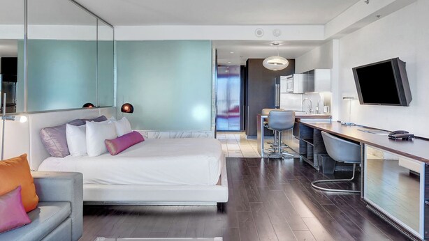 A modern hotel room with a large bed, a desk, and a TV.
