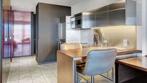 A modern kitchen with stainless steel appliances, a wooden dining table, and a bar area.