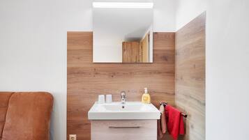 A bathroom with a white sink, wooden wall paneling, a mirror, and a red towel.