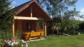 A wooden cabin with a porch and a swing set.