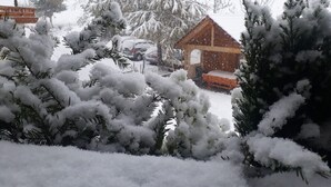A snow-covered landscape with a wooden cabin and snow-laden trees.