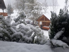 Schneebedeckte Landschaft mit einer Holzhütte und schneebedeckten Bäumen.