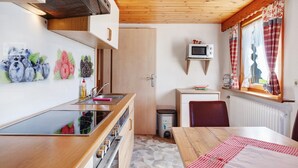 A compact kitchen with wooden cabinets, a microwave, and a window with plaid curtains.