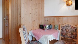 A wooden-paneled room with a table, chairs, a decorative lamp, and a floral-patterned headboard. - Room 'Doppelzimmer' with Mountain View, Shared Garden and Wi-Fi (Furtwangen)
