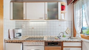 A kitchen with white cabinets, a coffee maker, a dishwasher, and a window with a view. - Apartment 'Sonnenwinkel' with Mountain View, Shared Garden and Wi-Fi (Furtwangen)