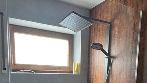 A shower with a glass door, a window above it, and a towel rack with towels. - Apartment 'Heinrich' with Private Terrace, Garden, and Wi-Fi (Schramberg)