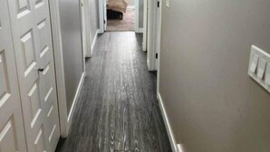 Un estrecho pasillo con suelo de madera y paredes blancas.