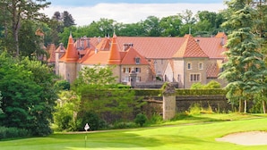 Un campo de golf con un edificio que parece un castillo al fondo.