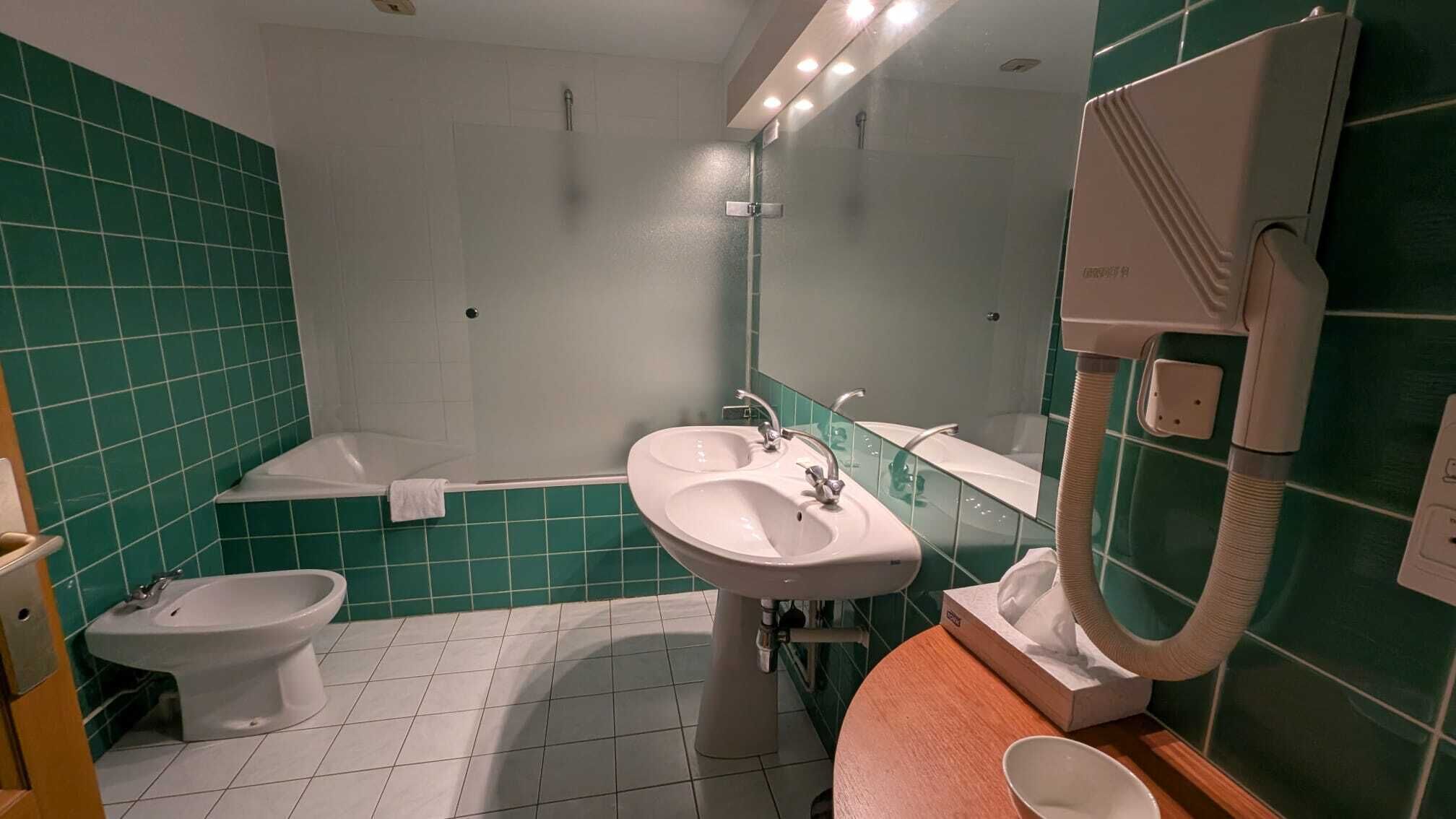 A bathroom with a bathtub, two sinks, a bidet, and a toilet.