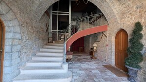 Una escalera de piedra que conduce a un segundo piso, con barandilla curva y una puerta de madera al final.