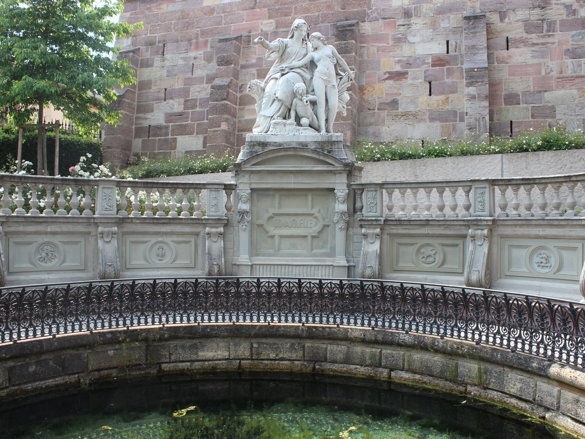 Een stenen brug met een decoratieve balustrade en een beeld op de top.