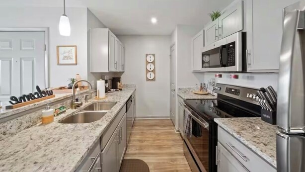 Cocina moderna con encimeras de granito, electrodomésticos de acero inoxidable y muebles de cocina blancos.