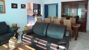 Ein Wohnzimmer mit einer Couch, einem Couchtisch und einem Essbereich mit Stühlen und einem Schrank.