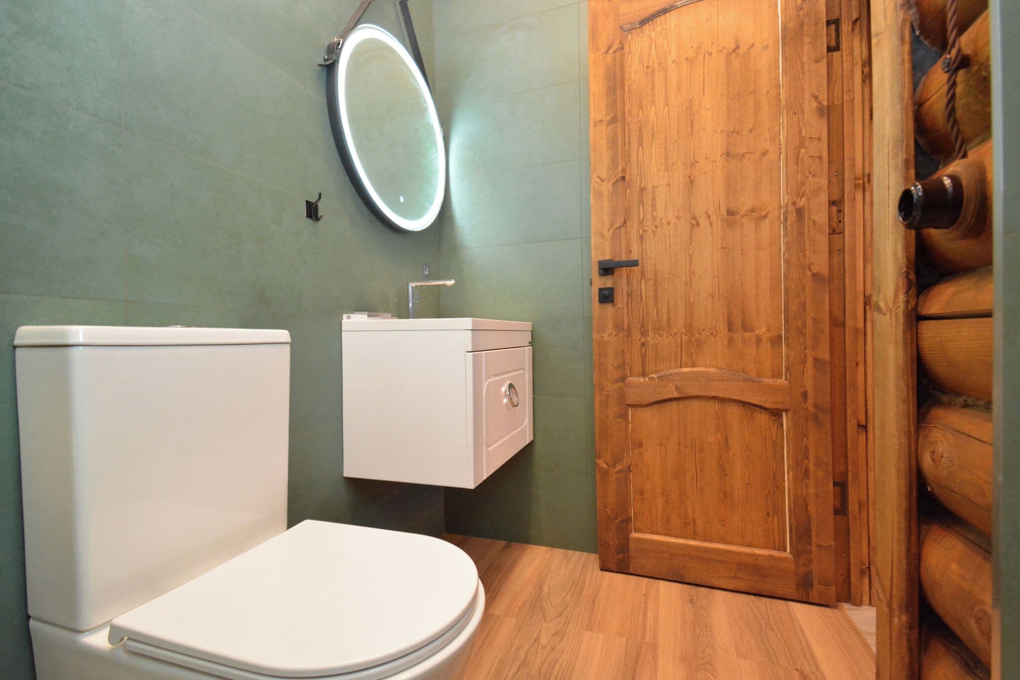 A bathroom with a toilet, a sink with a mirror, and a wooden door.