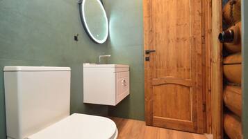 A bathroom with a toilet, a sink with a mirror, and a wooden door.