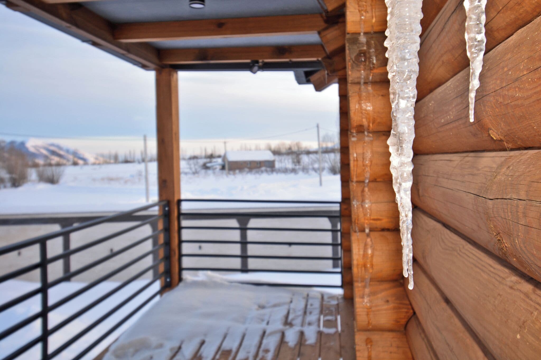 A wooden cabin with a balcony overlooking a snowy landscape.