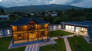 Een modern huis met twee verdiepingen, een grote glazen gevel, een zwembad en een verzorgd gazon.
