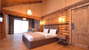 Een slaapkamer in blokhutstijl met een groot bed, houten wanden en een houten vloer.