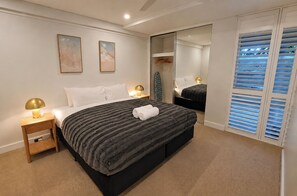 A hotel room with a large bed, bedside lamps, a mirror, and a wardrobe with sliding doors. - Scarborough Luxe • Ocean Views • King size Beds (Scarborough)