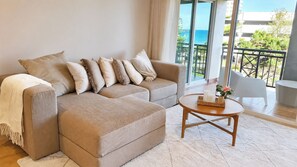 Una sala de estar moderna con un sofá modular, una mesa de centro redonda y vistas al océano a través de amplios ventanales.