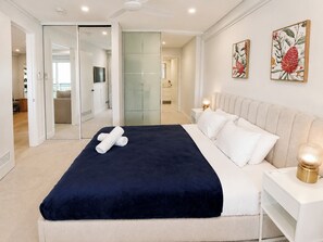 Un dormitorio moderno con una cama grande, lámparas de noche y vistas al baño.