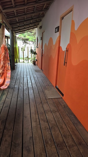 Une terrasse en bois mène à un bâtiment aux murs orange et à une porte portant l  ’inscription « LUA ».