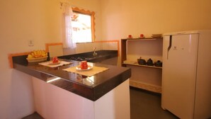 Una pequeña cocina con techo de madera, un refrigerador blanco y una ventana con cortina.