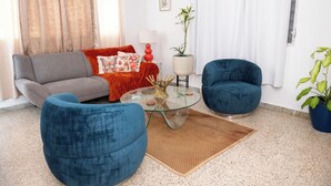 A living room with a grey sofa, blue armchairs, a glass coffee table, and a potted plant. - Cozy Home Close to Beaches (Cabo Rojo)