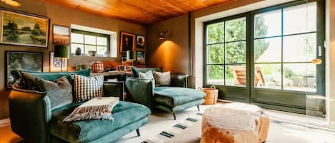 A cozy living room with a green sofa set, a coffee table, and a large window with a view of greenery.