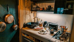 A kitchen with wooden cabinets, a stove, and various cooking utensils. - Cottage "Am Wald" links (Bissee)