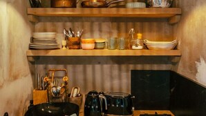 A kitchen with wooden shelves, hanging lights, a stove, and various kitchen utensils. - Cottage "Am Wald" rechts (Bissee)