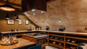 Una cocina rústica con una isla grande, repisas de madera e iluminación colgante.