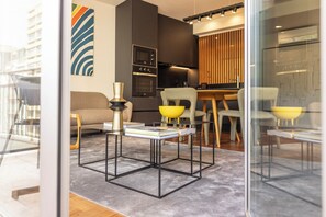 Una sala de estar moderna con un separador de vidrio, un sofá, una mesa de centro y una zona de comedor con sillas y una mesa.