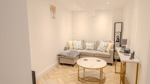 A modern living room with a sofa, a round coffee table, and a small side table with a lamp. - Pass the Keys | The Soak House - Great Hot Tub! (Rye)