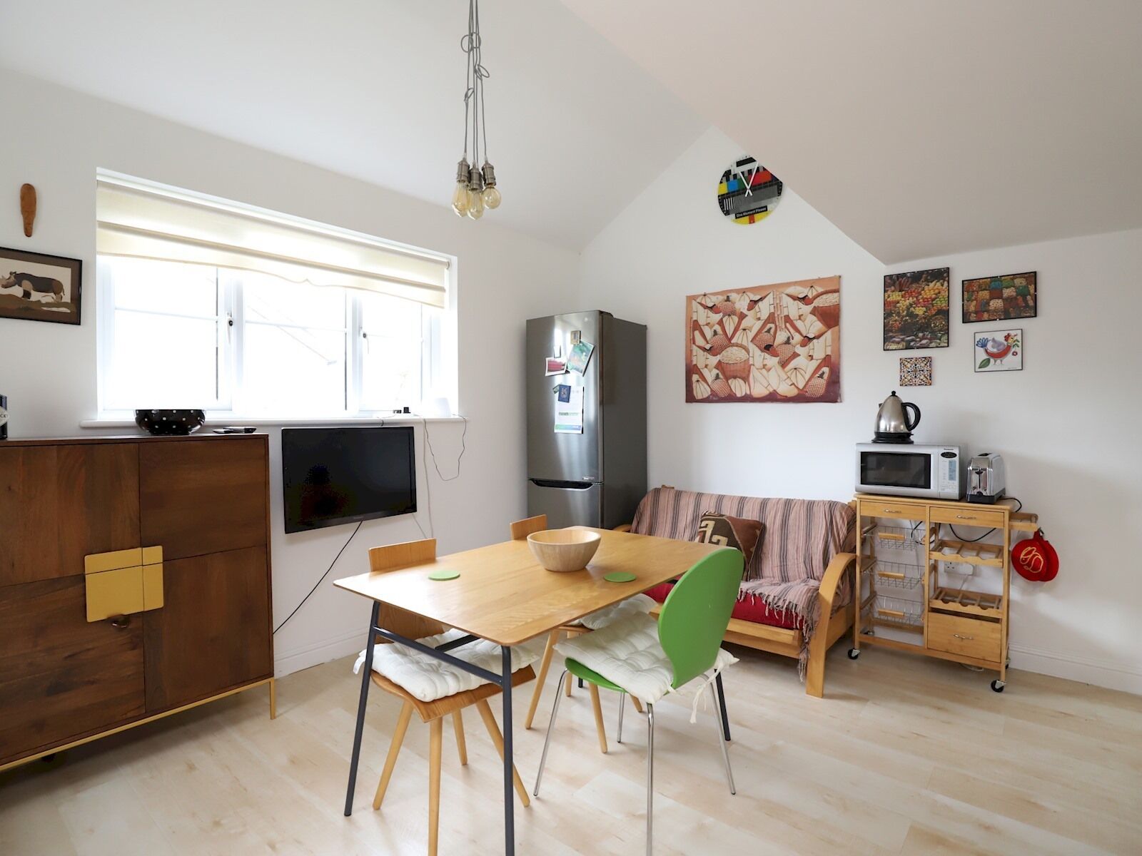 Un espace de vie compact comprenant un coin repas, une kitchenette et une grande fenêtre.