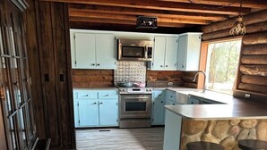 Eine rustikale Küche mit hellblauen Schränken, einer Steinarbeitsplatte und einer Holzbalkendecke.