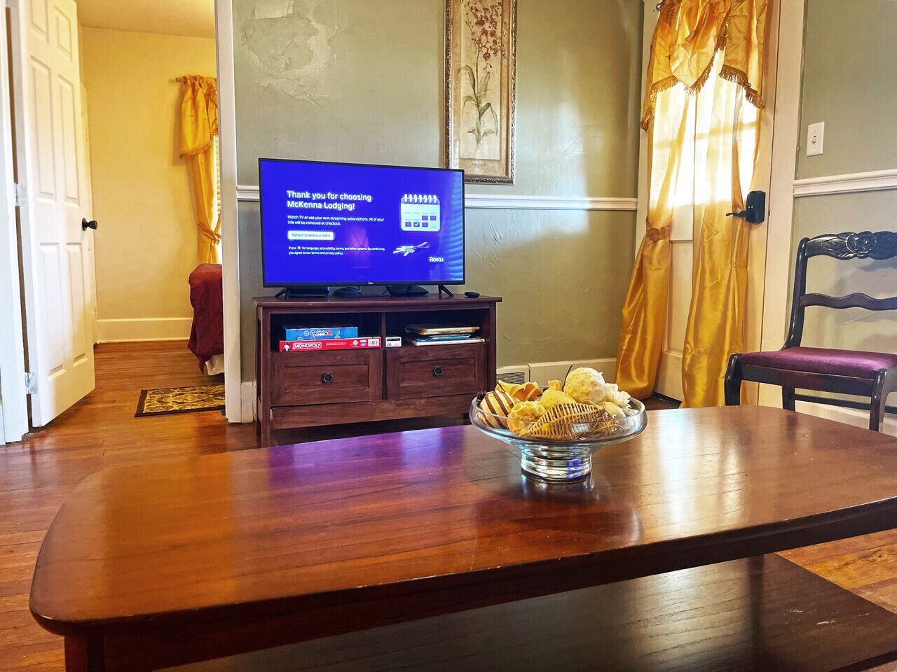 A dining area with a wooden table, a television displaying a message, and a bowl of snacks.