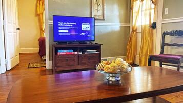 A dining area with a wooden table, a television displaying a message, and a bowl of snacks.