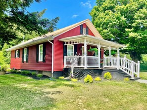 Ein rotes Haus mit einer weißen Veranda und einer kleinen Treppe, die hinauf führt.