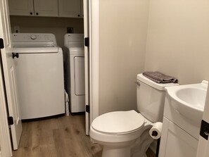 Une petite salle de bain comprenant des toilettes, un lavabo et un lave-linge.