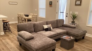 Una sala de estar moderna con un sofá modular, una mesa de centro y un comedor con una mesa y sillas.
