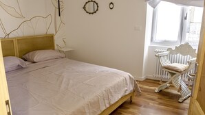 A bedroom with a wooden bed, a radiator, and a window with curtains. - Casa Clelia (Verrès)
