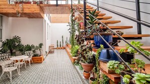 Un escalier avec des marches en bois et des rampes en métal, entouré de différentes plantes en pot.