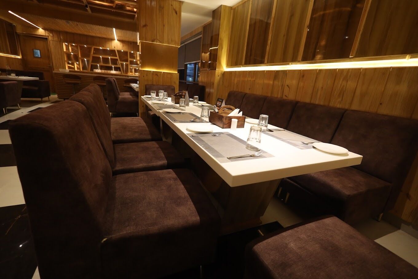 A modern restaurant with long communal tables and cushioned booths.