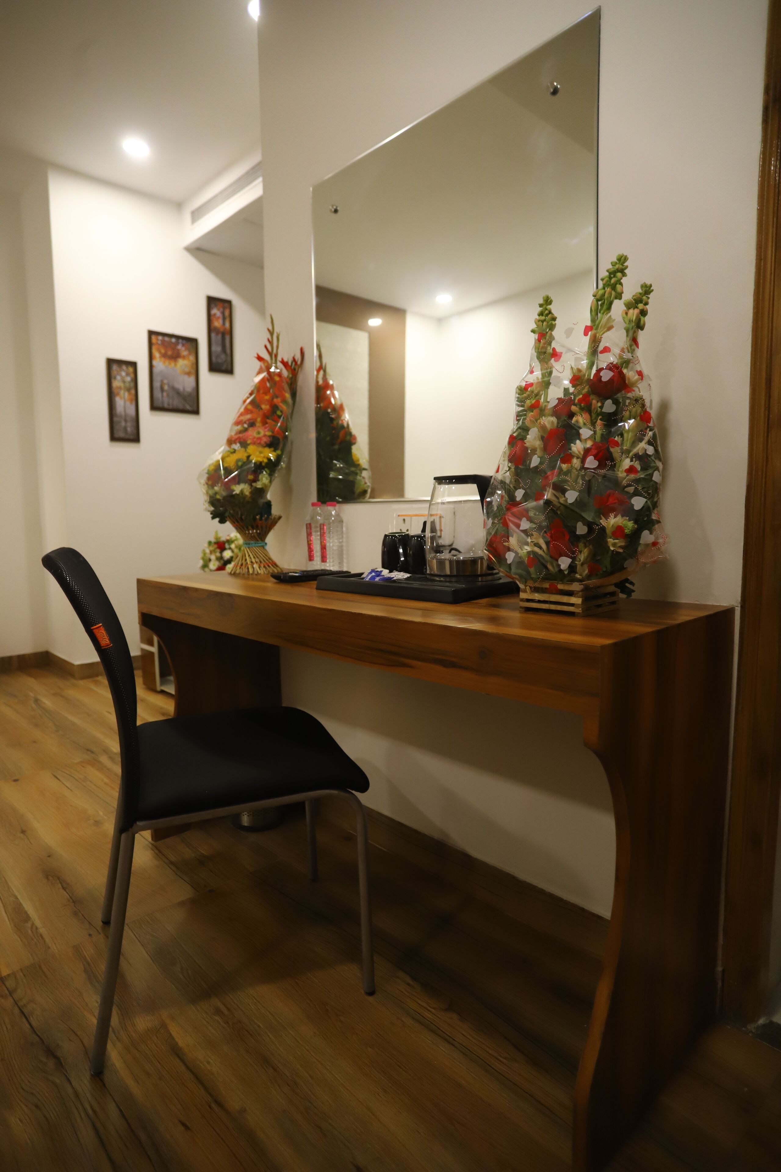 Een houten bureau met een spiegel, een stoel en twee bloemenboeketten.