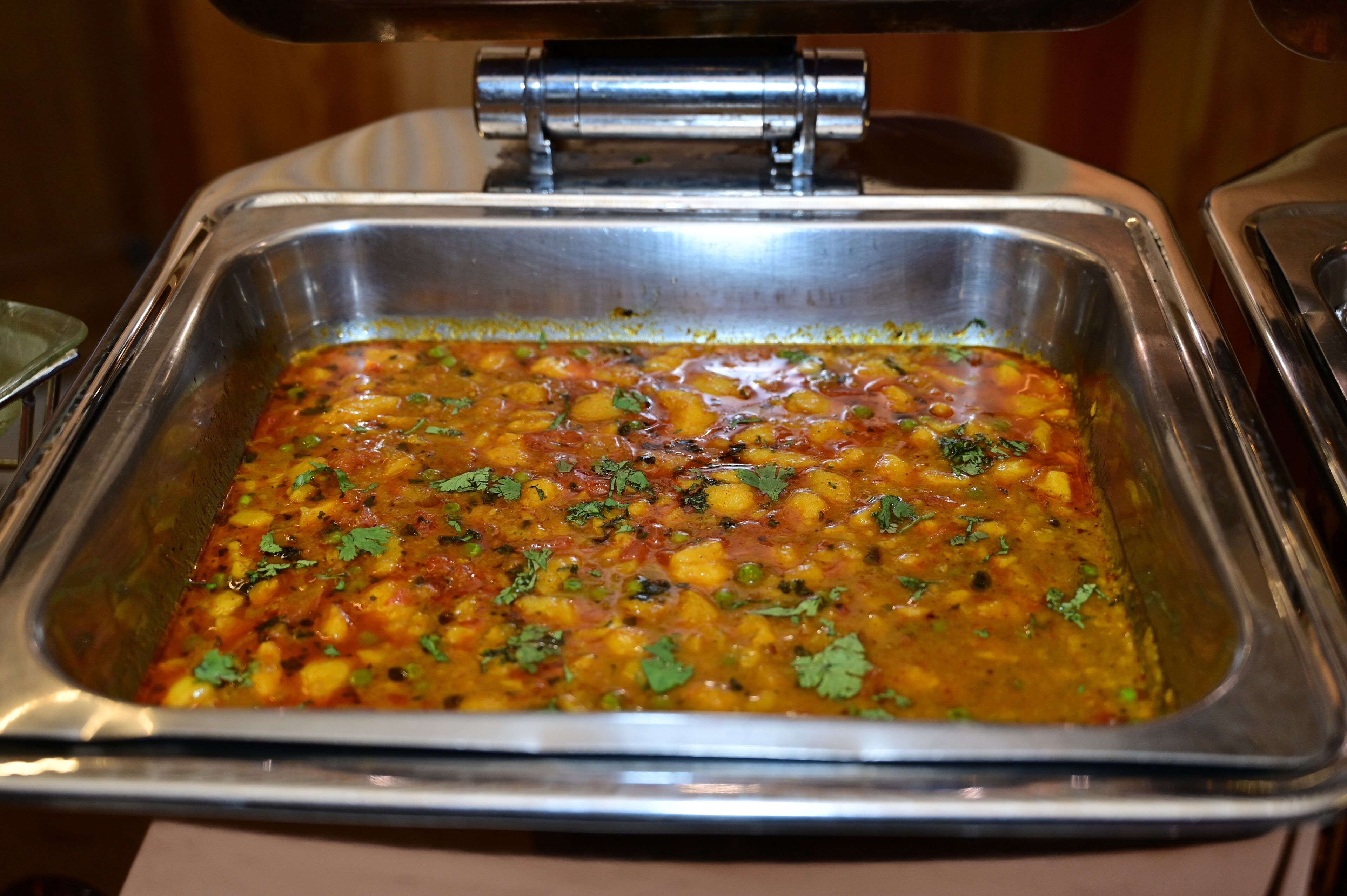 Een buffet met diverse gerechten, waaronder een curry met groenten en kruiden.